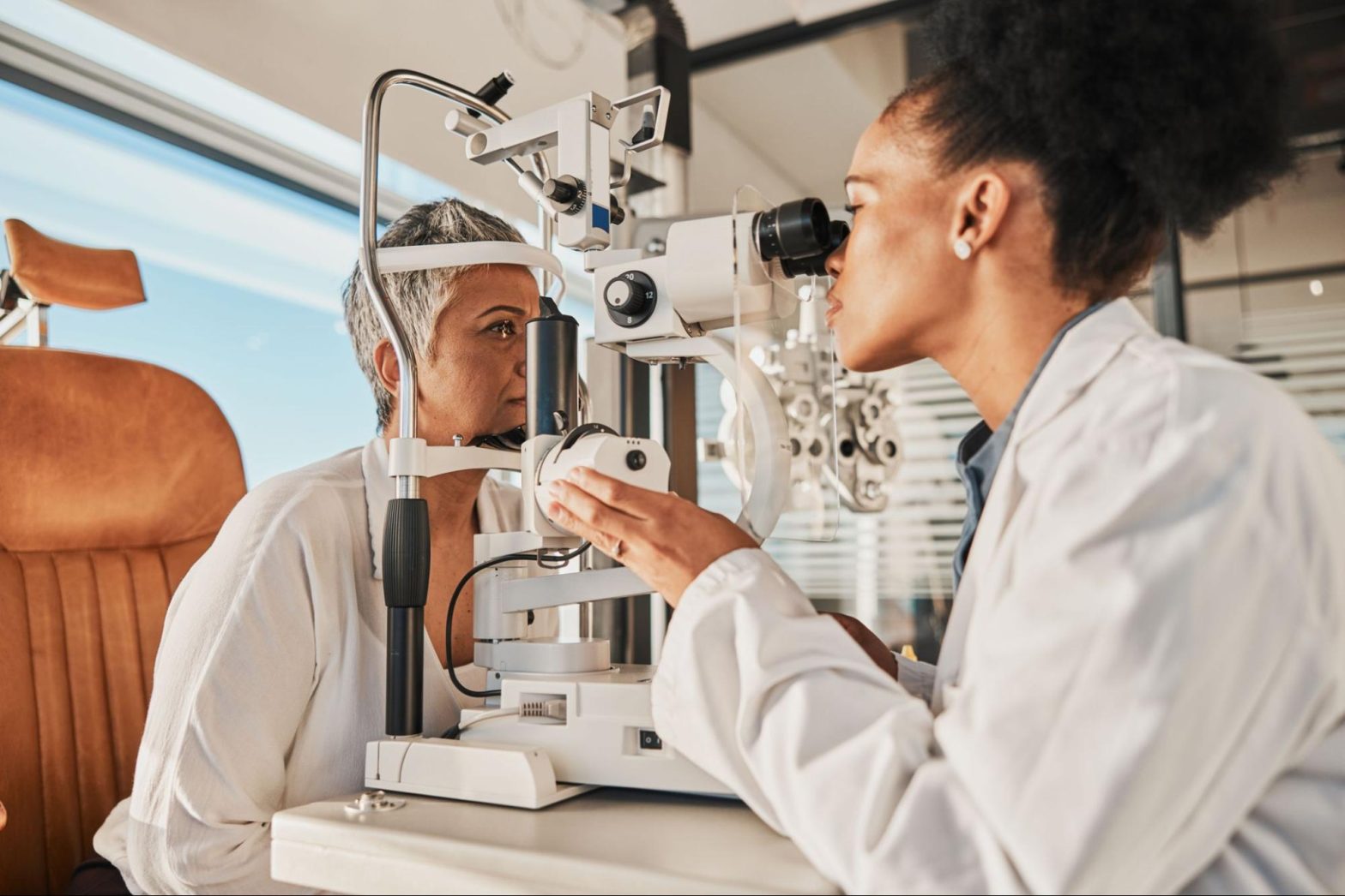 Woman with cataracts getting her eyes checked by opthalmologist